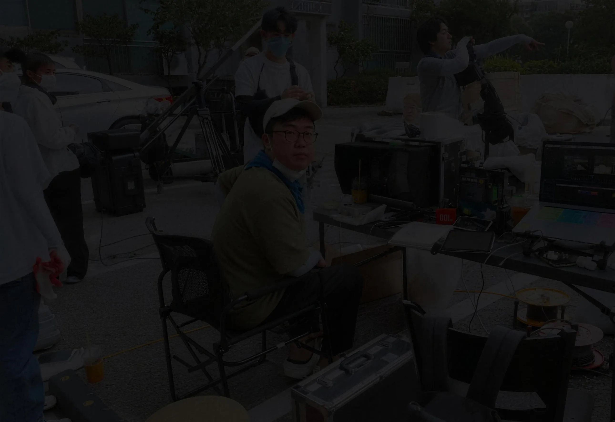 감독이 촬영 현장에서 의자에 앉아 모니터를 보고 있다